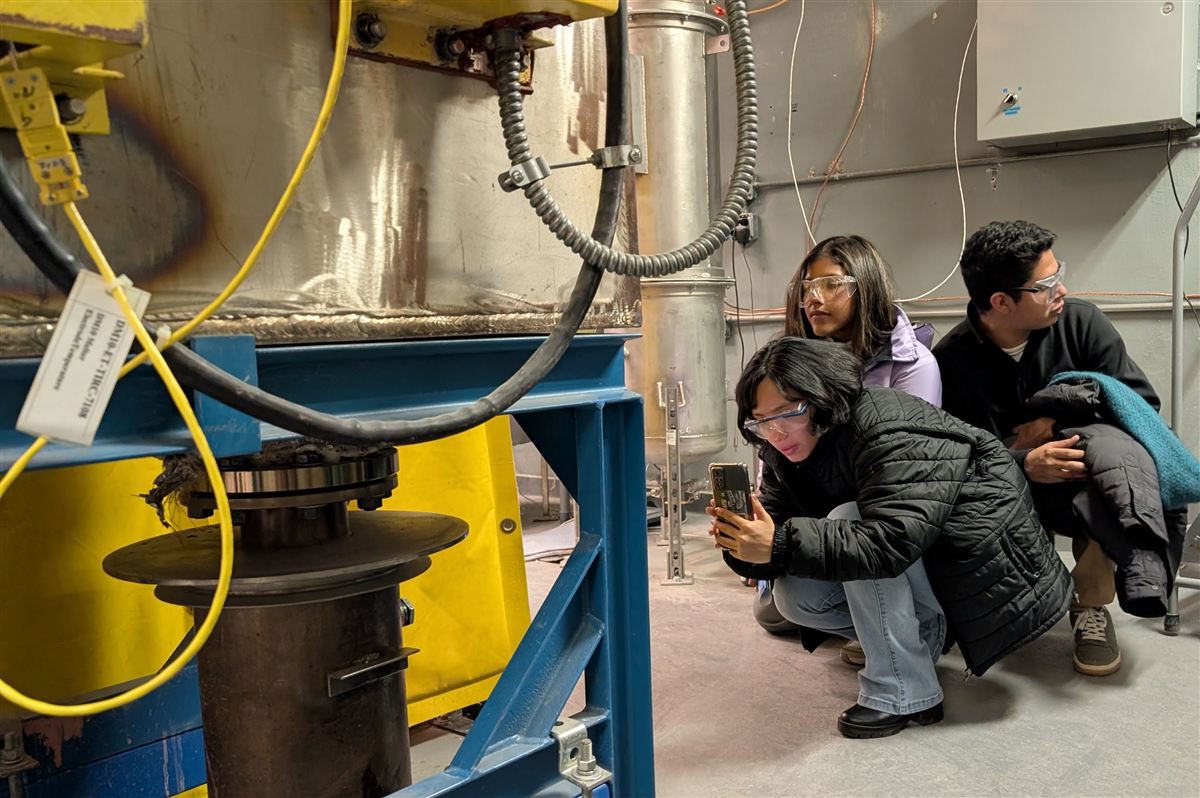 Participants examining industrial equipment with safety goggles